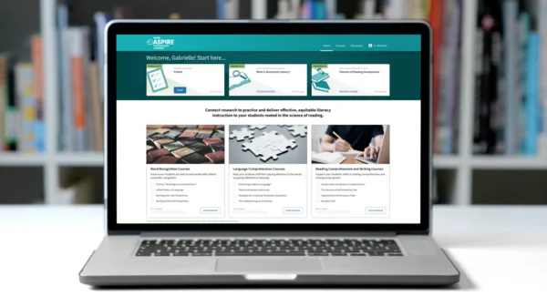 A laptop displaying an educational website with reading course options and book images on the screen.