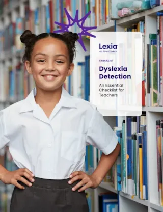 Smiling girl in a school uniform stands in a library next to a sign about dyslexia detection for teachers.