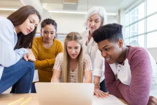 5 teenage students and their teacher surround a laptop screen