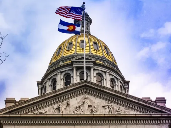 Colorado state flag flying alongside the American flag at a state capitol building.