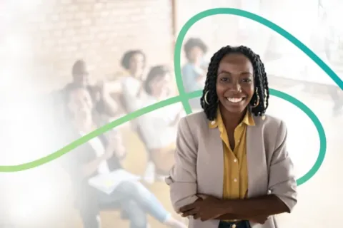 Smiling woman in a blazer stands confidently with arms crossed in front of a blurred group of people and abstract lines.