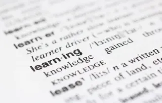 Close-up of a dictionary page focusing on the word learning with its pronunciation and definition visible.