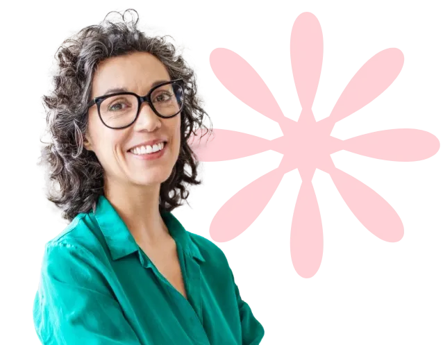 Smiling woman with curly hair and glasses, wearing a green shirt, stands in front of a red flower-like graphic.