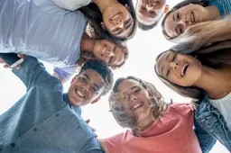 A group of middle school students stand in a circle looking down at the camera.