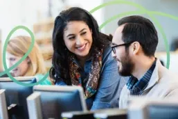 smiling school administrator and teacher work together at a computer