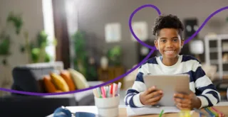 Smiling child in striped shirt uses a tablet at a desk with colorful pens in a cozy, well-lit room.