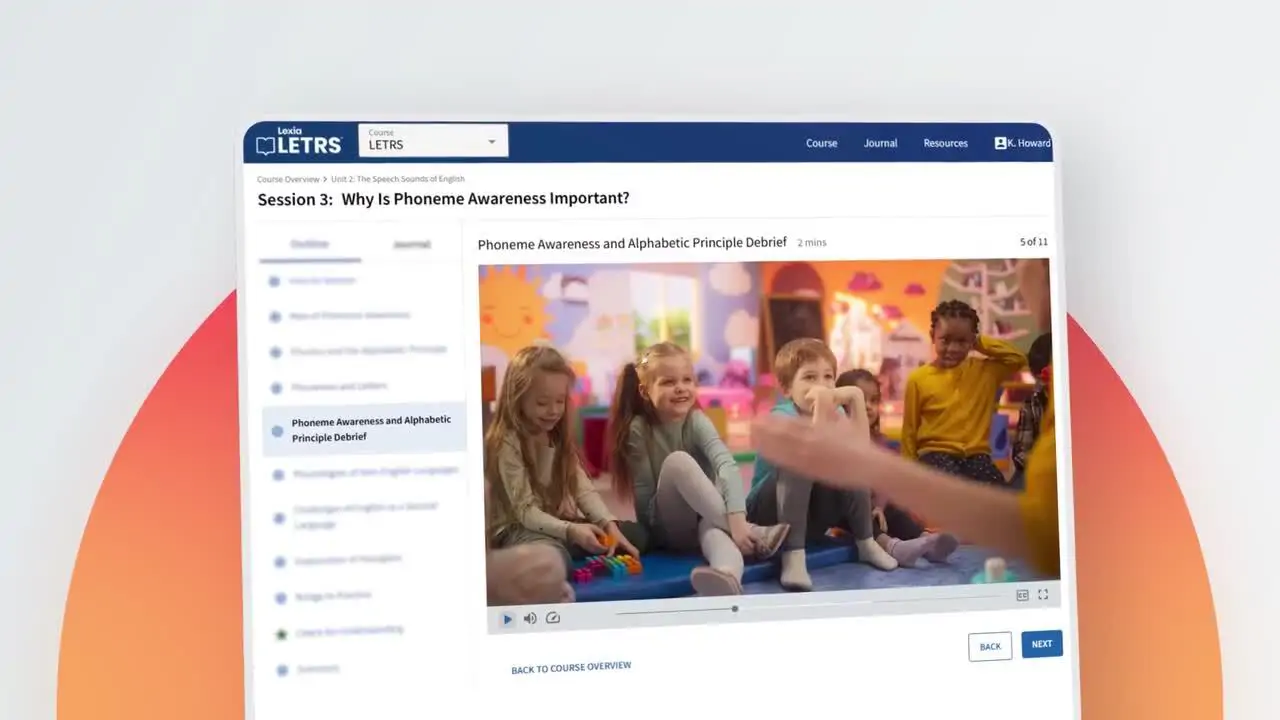 A group of young children sit in a classroom, smiling and interacting with a teacher during a lesson.