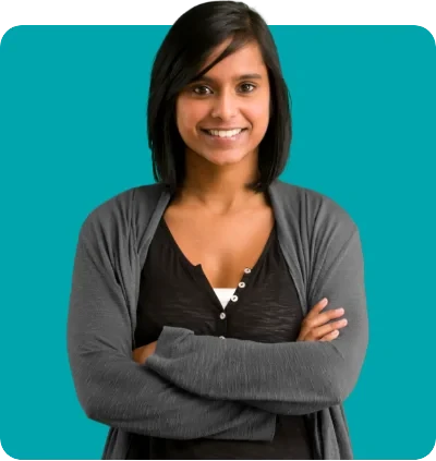 Woman with dark hair and a gray cardigan stands smiling with her arms crossed against a teal background.