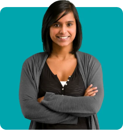 Woman with dark hair and gray cardigan smiling, standing with arms crossed in front of a teal background.