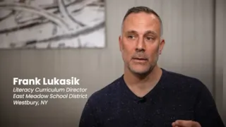 A man with short hair and a beard speaks, text reads: Frank Lukasik, Literacy Curriculum Director, East Meadow School District.
