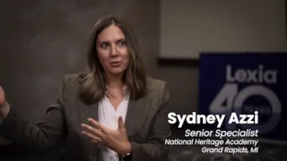 Woman speaking in an interview setting, with a blurred background and name/title displayed: Sydney Azzi, Senior Specialist.